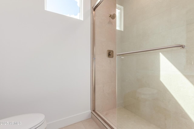 full bathroom with a stall shower, tile patterned floors, toilet, and baseboards