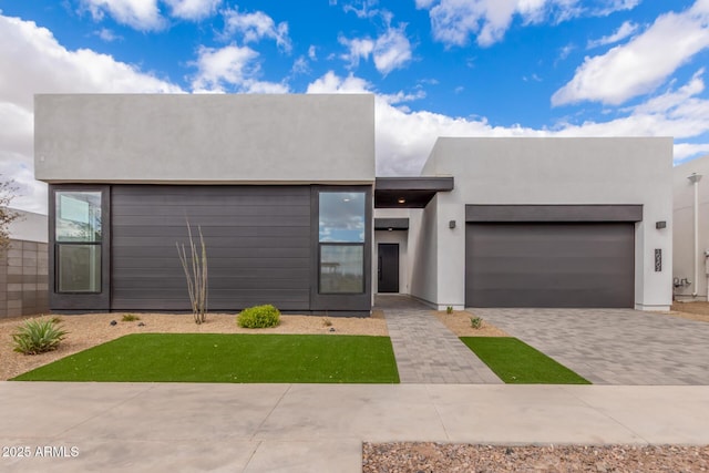 view of front of property featuring a garage, decorative driveway, and stucco siding