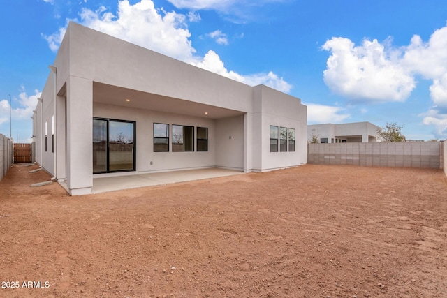 rear view of property featuring a patio area, a fenced backyard, and stucco siding