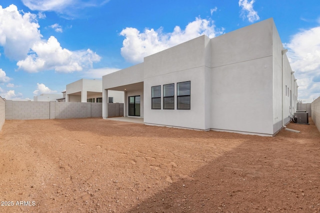 back of house with a fenced backyard, cooling unit, and stucco siding