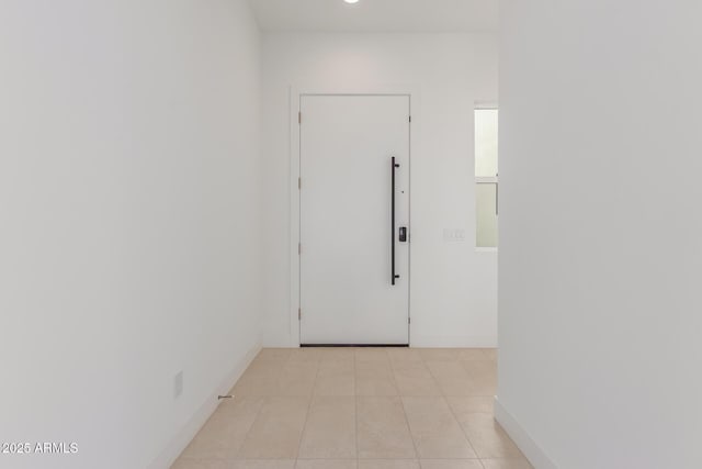 hall featuring baseboards and light tile patterned flooring