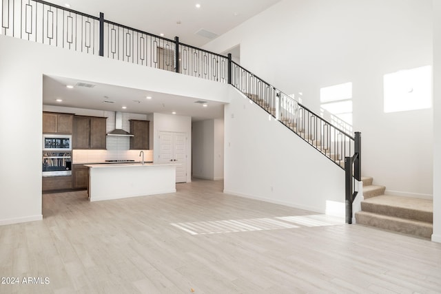 27271 N 73rd Ln, Peoria, AZ 85383 - unfurnished living room with a sink, light wood-type flooring, stairway, baseboards, and a towering ceiling