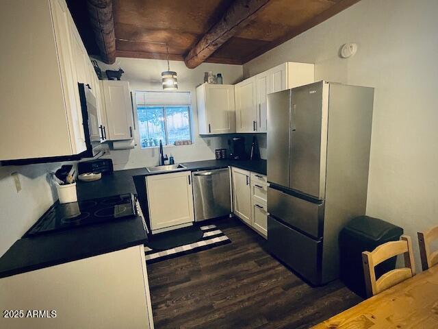 kitchen featuring white cabinets, beam ceiling, stainless steel appliances, and sink