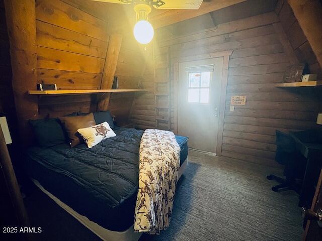 bedroom with dark carpet, ceiling fan, and wood walls