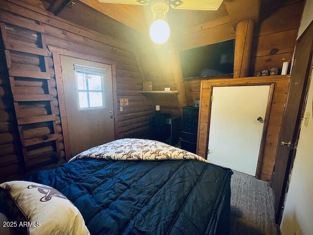 bedroom with vaulted ceiling, rustic walls, and ceiling fan