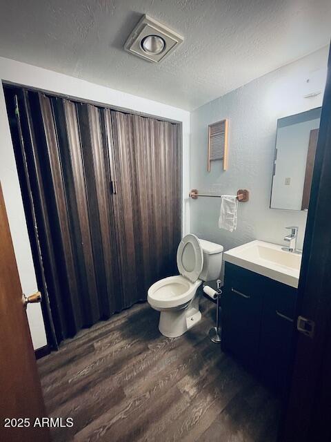 bathroom featuring hardwood / wood-style floors, vanity, toilet, and a textured ceiling