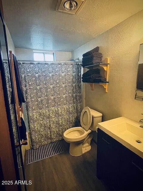 bathroom with a shower with shower curtain, hardwood / wood-style floors, vanity, and toilet