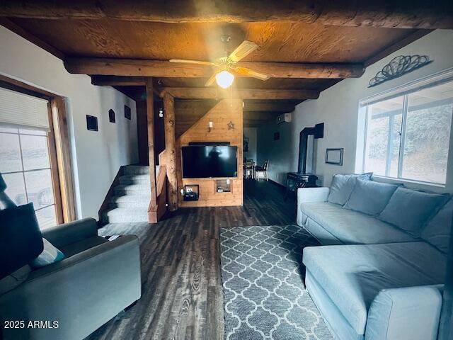 living room with wooden ceiling, dark wood-type flooring, a wood stove, ceiling fan, and beam ceiling