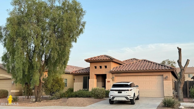 mediterranean / spanish home with driveway, a tiled roof, an attached garage, and stucco siding