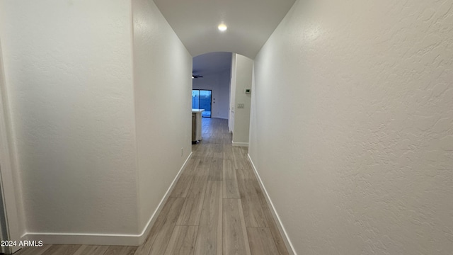 hall with arched walkways, baseboards, and wood finished floors