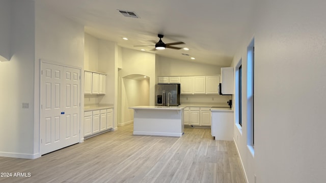 kitchen featuring light countertops, white cabinets, an island with sink, light wood-type flooring, and stainless steel fridge