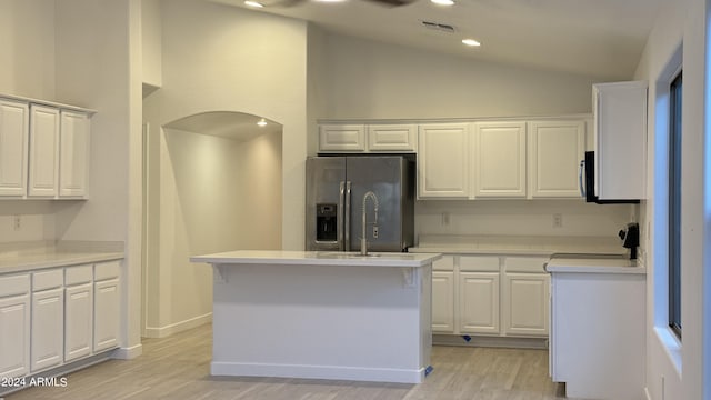 kitchen featuring a kitchen island with sink, visible vents, white cabinets, light countertops, and stainless steel refrigerator with ice dispenser