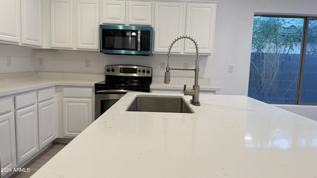 kitchen featuring stainless steel appliances, white cabinetry, and light stone countertops