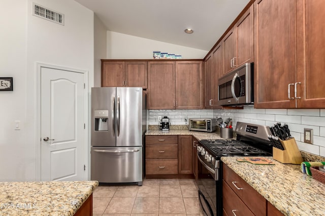 kitchen featuring light tile patterned flooring, stainless steel appliances, lofted ceiling, backsplash, and visible vents
