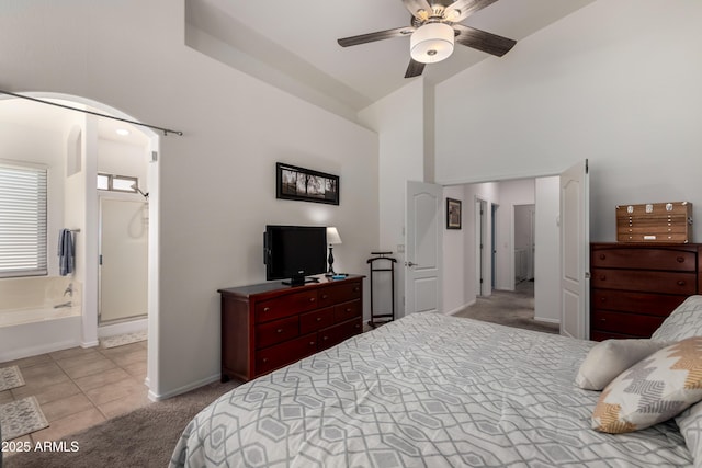 tiled bedroom featuring carpet floors, baseboards, high vaulted ceiling, connected bathroom, and a ceiling fan