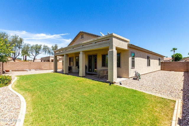 back of property with a fenced backyard, a patio, stucco siding, and a yard