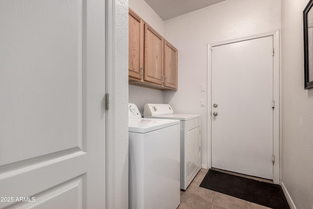laundry area with washing machine and clothes dryer, light tile patterned floors, and cabinet space