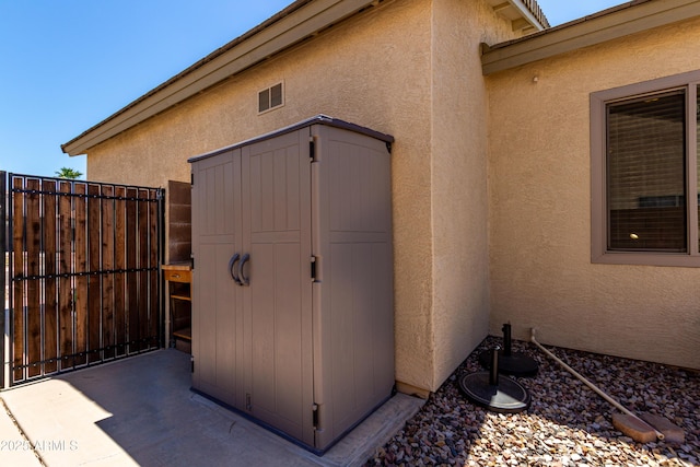 view of shed featuring fence and a gate