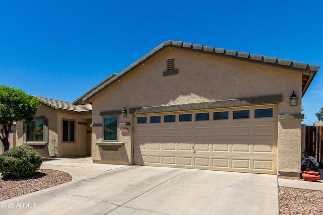 single story home featuring a garage, driveway, a tile roof, and stucco siding