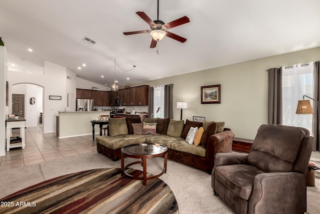 living area featuring visible vents, lofted ceiling, baseboards, arched walkways, and a ceiling fan