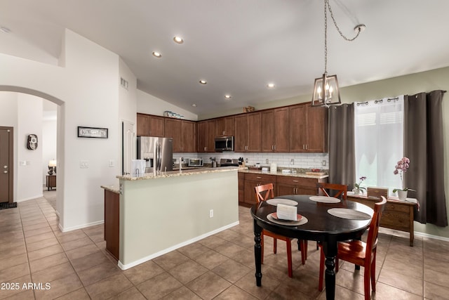 kitchen with light tile patterned floors, appliances with stainless steel finishes, arched walkways, and lofted ceiling