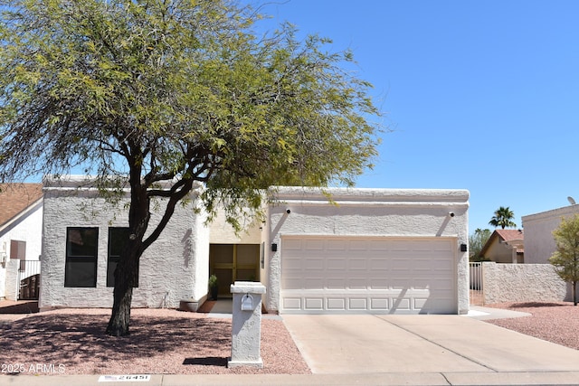 view of front of house featuring stucco siding, concrete driveway, fence, and a garage
