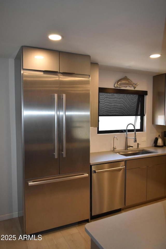 kitchen with appliances with stainless steel finishes, a sink, light countertops, and recessed lighting