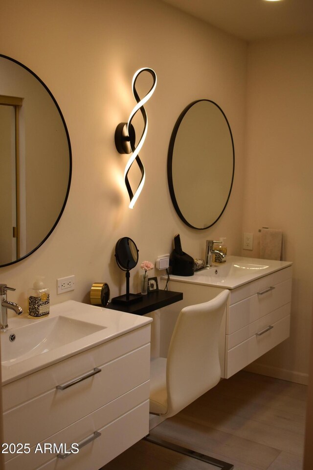 bathroom with two vanities, wood finished floors, and a sink