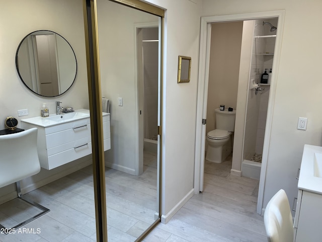 bathroom featuring toilet, vanity, wood finished floors, and a stall shower