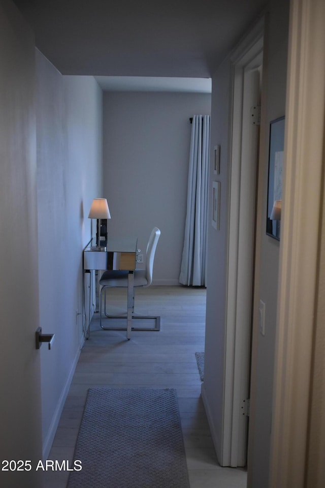 hallway featuring wood finished floors and baseboards