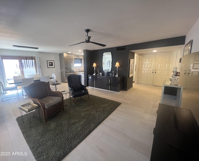 living area featuring ceiling fan, light wood-style floors, visible vents, and plenty of natural light