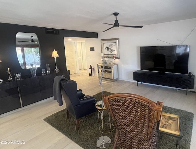 living area with wood finished floors, visible vents, and a ceiling fan