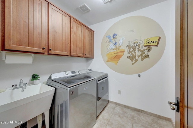 clothes washing area with cabinet space, separate washer and dryer, light tile patterned floors, and baseboards