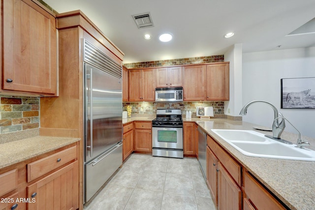 kitchen with stainless steel appliances, a sink, decorative backsplash, and light tile patterned floors