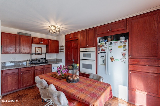 kitchen with sink, a notable chandelier, white appliances, and dark stone counters