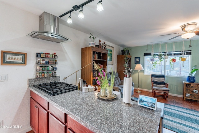 kitchen with track lighting, ceiling fan, wood-type flooring, gas stovetop, and wall chimney exhaust hood