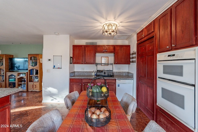 kitchen with a chandelier, crown molding, white appliances, and dark tile patterned flooring