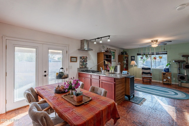 kitchen featuring ceiling fan, wall chimney exhaust hood, light stone counters, and stainless steel gas stovetop