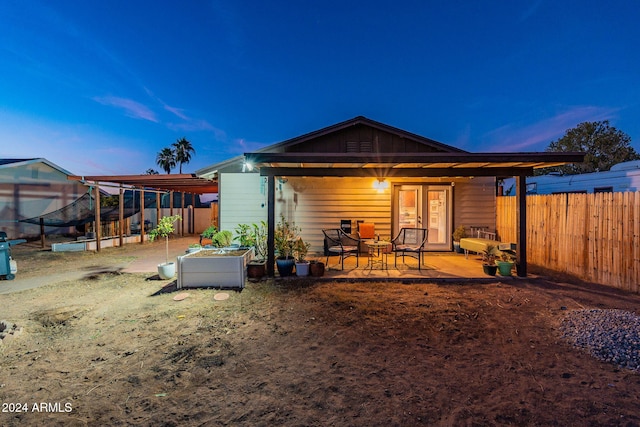 back house at dusk featuring a patio area