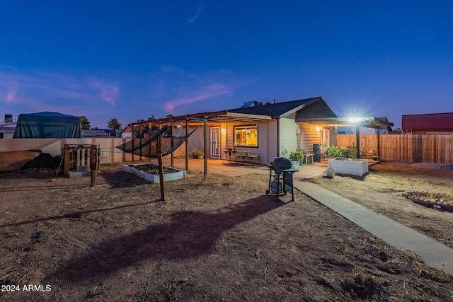 back house at dusk featuring a patio