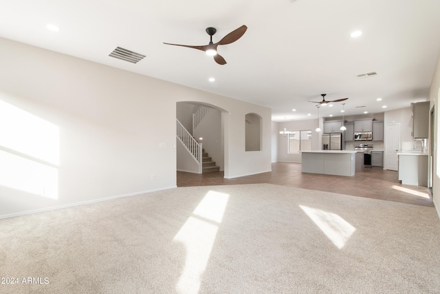 unfurnished living room featuring sink, light colored carpet, and ceiling fan