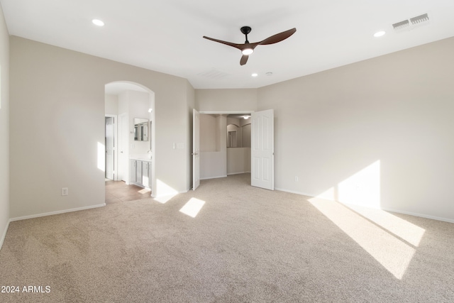 unfurnished bedroom with ensuite bathroom, light colored carpet, and ceiling fan