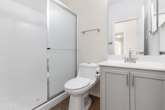 bathroom with vanity, toilet, a shower with shower door, and tile patterned flooring