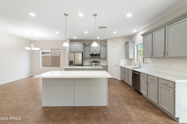 kitchen featuring a kitchen island, appliances with stainless steel finishes, pendant lighting, gray cabinetry, and sink