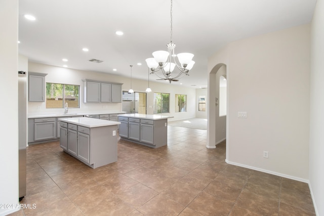 kitchen with a wealth of natural light, pendant lighting, a center island, and gray cabinetry