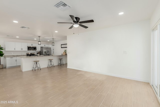 living area with recessed lighting, baseboards, visible vents, and light wood finished floors