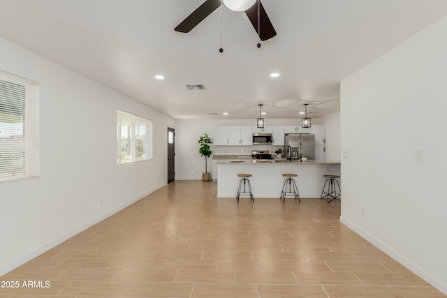 kitchen featuring pendant lighting, a breakfast bar area, stainless steel appliances, visible vents, and white cabinets