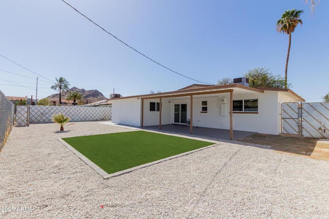 back of property featuring a lawn, a patio area, a fenced backyard, and a gate