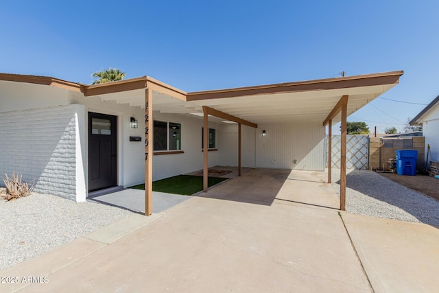 exterior space with fence, an attached carport, and concrete driveway