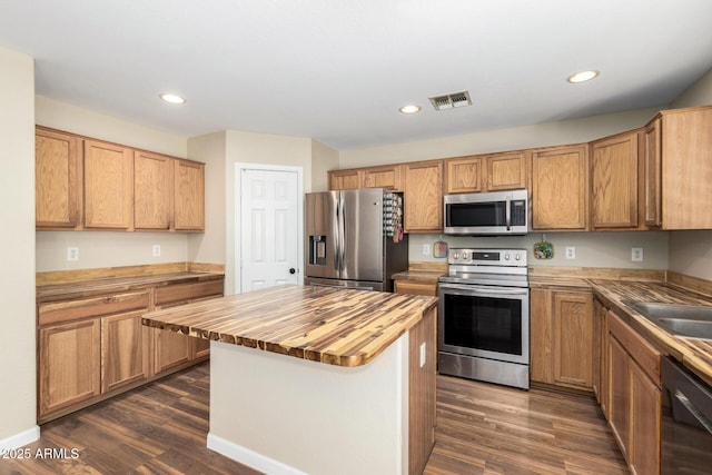 kitchen with recessed lighting, stainless steel appliances, dark wood finished floors, and butcher block countertops